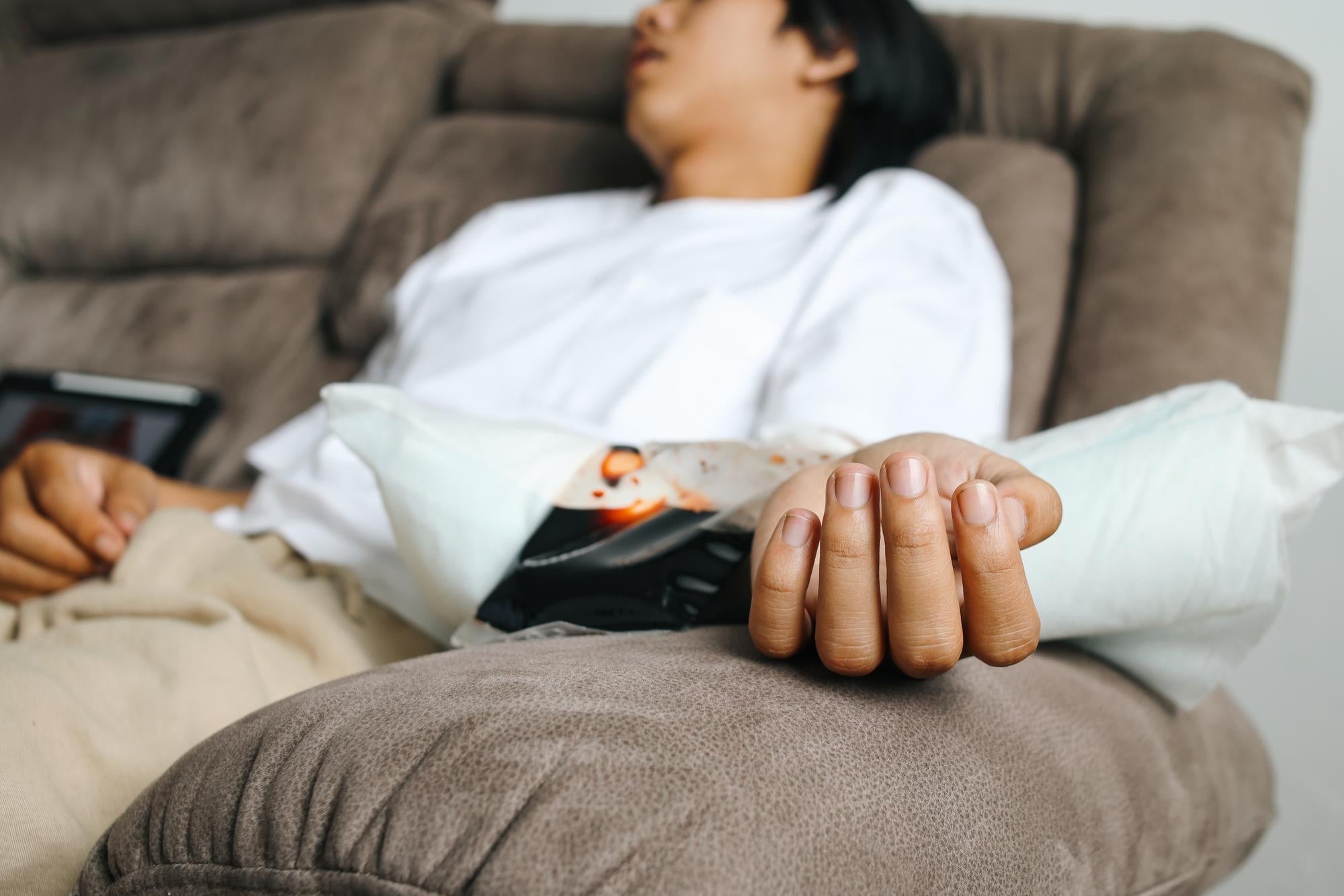 A person resting on a couch with an IV line showing how to live with Essential Tremor and fatigue.