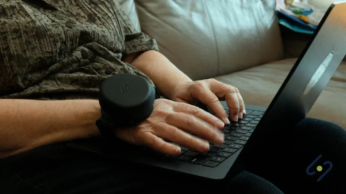 Person wearing Steadi-3 tremor stabilization glove while typing on laptop, supporting hand control during daily tasks with Parkinson’s.