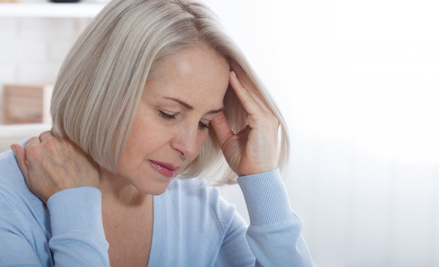 Older woman holding head and neck showing signs of Parkinson's disease in women, including pain and non-motor symptoms.