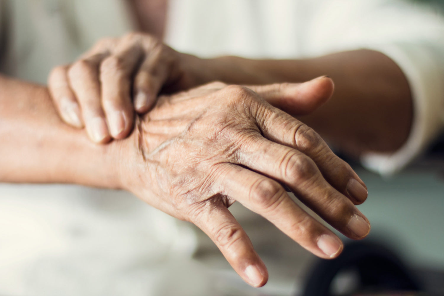Caregiver gently holding the trembling hand of an elderly person, supporting someone experiencing tremors in elderly people.