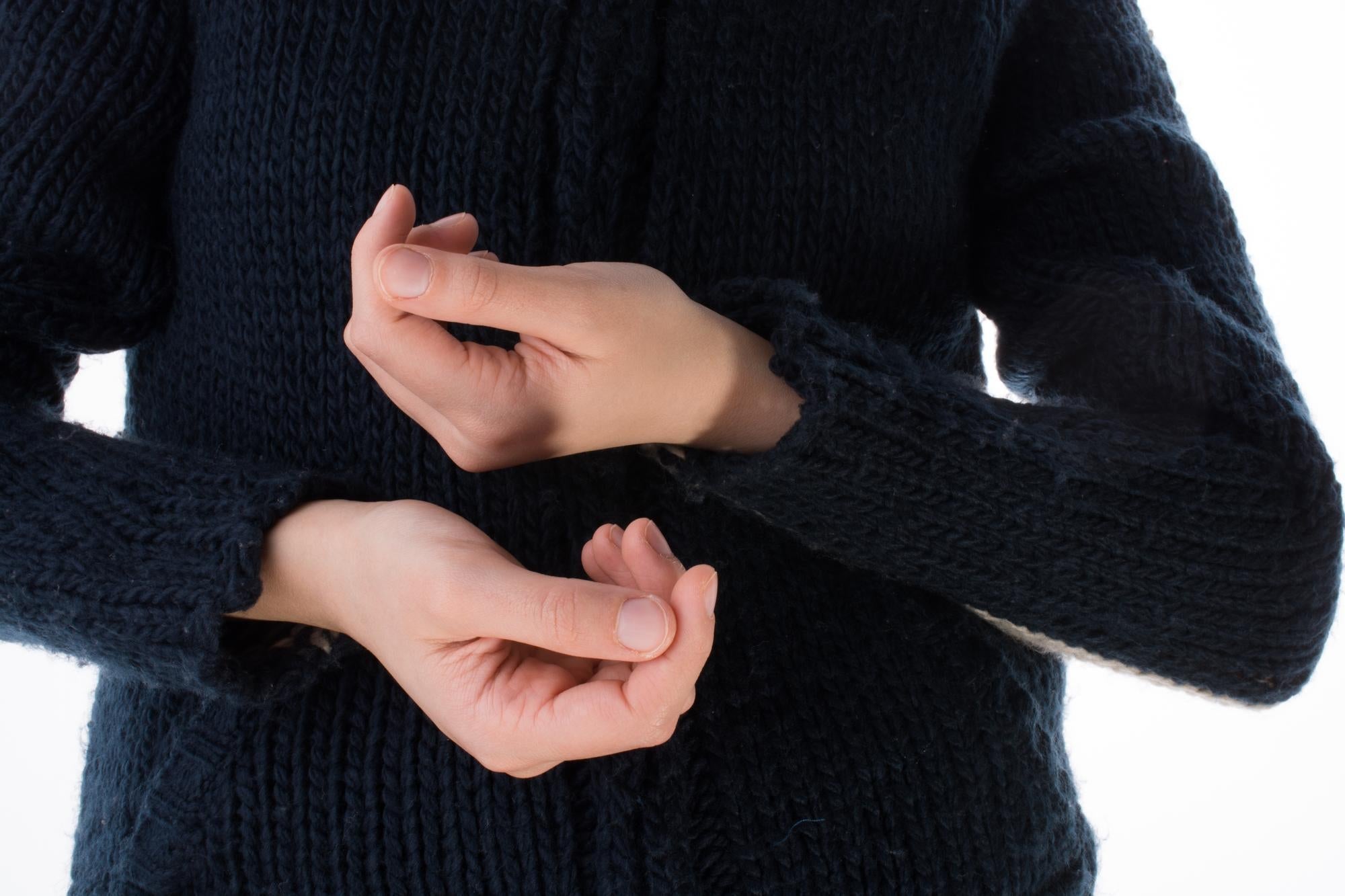 A person with Essential Tremor dressing, struggling to fasten clothing.