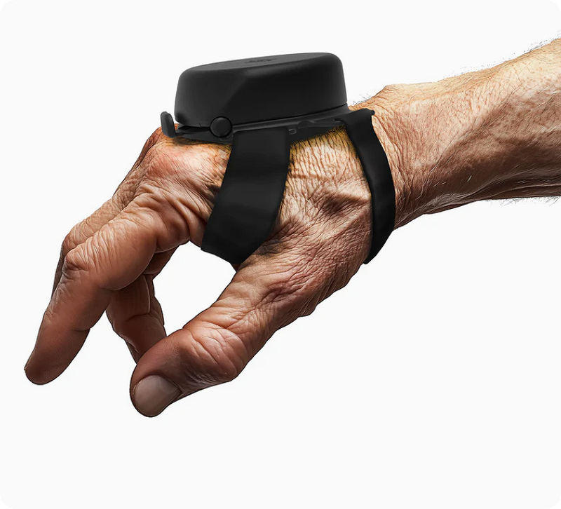 Steadi-3 tremor stabilization device worn on an older man's hand, showing the black dome unit and strap used to manage Parkinson's Disease tremors.